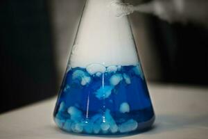 químico matraz con azul solución. experiencias y experimentos foto