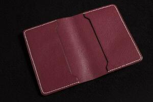 Open burgundy leather wallet with pockets on a dark background. photo