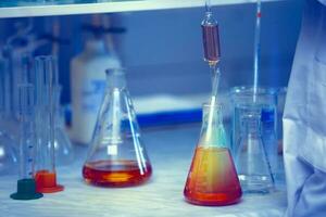 Vaccine production laboratory. Glass flasks with a chemical liquid in infrared radiation. photo