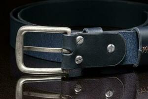 cuero cinturón con un metal hebilla de cerca en un oscuro antecedentes. foto