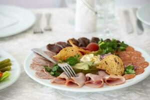 On a plate, an appetizer of sliced meat with croutons and vegetables. photo