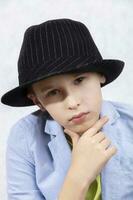 A handsome stylish boy in an elegant hat looks thoughtfully into the camera. Serious look. photo