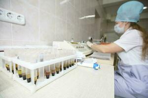 Medical test tubes with blood on the background of a blurred nurse. photo