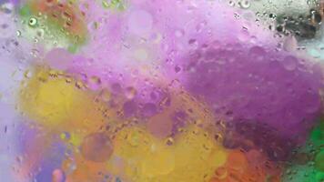 a colorful abstract painting on a window with water droplets video