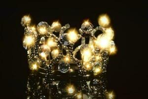 Gold crown with shiny stones on a black background. photo