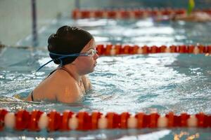 Child athlete swims in the pool. Swimming section. photo