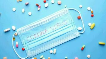 coronavirus escrito en un médico máscara y pastillas dispersado en un azul antecedentes video