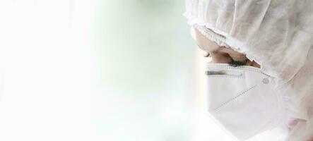 The face of a doctor in a protective medical mask and suit close-up on a white background. photo