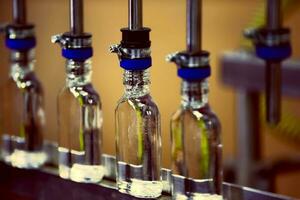 A row of glass bottles on a conveyor belt for the production of alcoholic beverages. photo