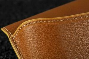 Part of a brown leather wallet or case with stitching. photo