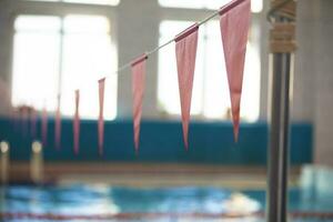rojo triangular banderas en contra el azul agua de el nadando piscina. foto