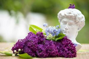 Lilac branches lie with the head of Michelangelo. The concept of creativity and art. photo