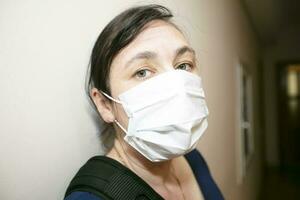 The face of a middle-aged woman wearing a protective medical mask. photo