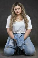 Beautiful fat woman in denim clothes on a gray background. Plus size model girl. photo