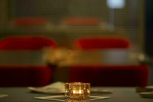 Burning candle on the table against the backdrop of a blurred cafe. photo