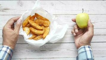 ein Person halten ein Apfel und ein Schüssel von Fritten video