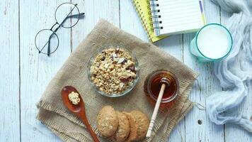 a bowl of cereal, a glass of milk, a notebook and a spoon are on a table video