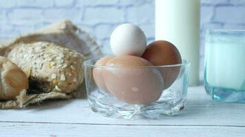 eggs in a bowl, whole meal bread and milk on table video