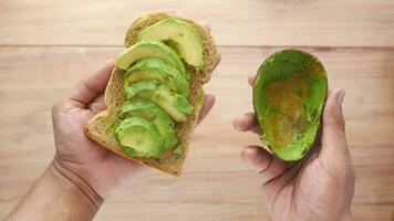 hand hold Avocado on slice of a brown bread on table video