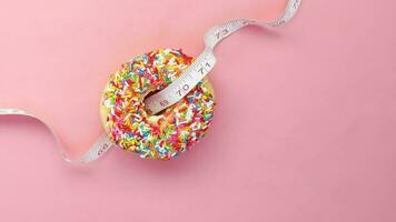 Close up of donuts and measurement tape on pink background video