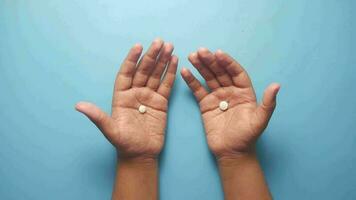 dos manos con blanco pastillas en un azul antecedentes video