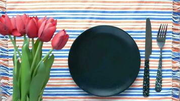 a black plate with a fork and knife on a striped tablecloth video