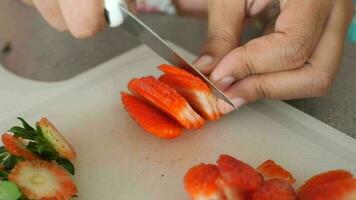 a person cutting up strawberries on a cutting board video