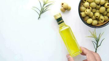 Hand hold a bottle of olive oil and olives on a white background video