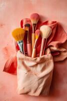 Bag filled with makeup brushes on top of pink cloth covered table. photo