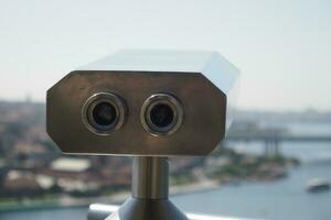 Coin-operated binoculars looking out over city , photo