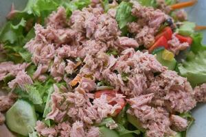 spoon pick tuna salad from a bowl on table photo