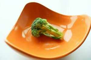 raw fresh organic Brokolo Broccoli in a orange color bowl photo