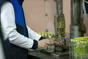 Worker hands and empty bottles on a conveyor belt in the production of alcoholic beverages. photo