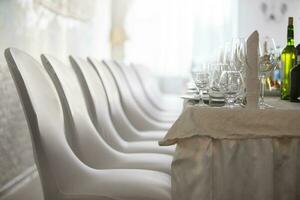 White chairs in a row and dishes on the restaurant table. Part of the restaurant interior. photo