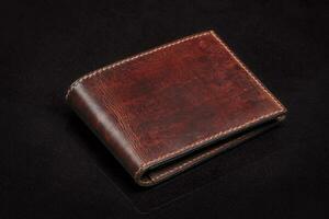 Leather wallet in brown on a black background. photo