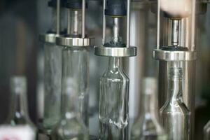 A row of glass bottles on a conveyor belt for the production of alcoholic beverages. photo