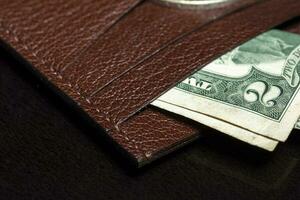 Part of a leather wallet or wallet with a banknote on a dark background. photo