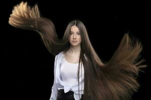Beautiful brunette with long flying hair on a dark background. photo