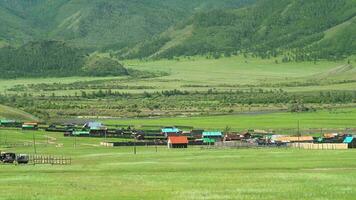 vistoso casas de un ruso pueblo en bosque y prado por río en Siberia, Rusia video