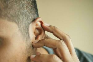 young man having ear pain touching his painful ear , photo