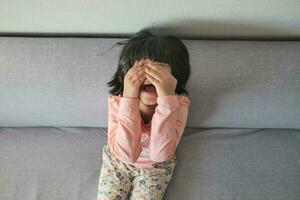 a upset child girl cover her face with hand photo