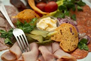 On a plate, an appetizer of sliced meat with croutons and vegetables. photo