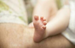 A small children's foot with funny fingers in male hands close-up. photo