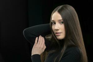 Beautiful young girl with long straight hair on a dark background. photo