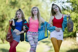 Three beautiful country girls dressed in the style of the nineties are walking along the road. photo