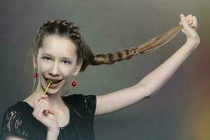 A funny and mischievous teenager girl with a lollipop and a long braid. photo