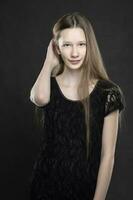 Portrait of a beautiful teenage girl is shot against a gray background. Slim girl blonde with blue eyes. photo