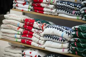 There are stacks of knitted sweaters with a Christmas pattern on a store shelf. New Year's sale. photo