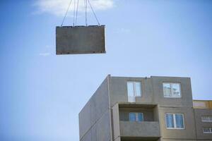 Construction of a panel house. A construction crane lifts a concrete wall from a panel house. photo
