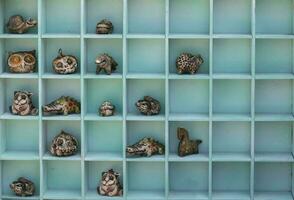 Handmade clay children's toys of fabulous animals lie in wooden cells. photo